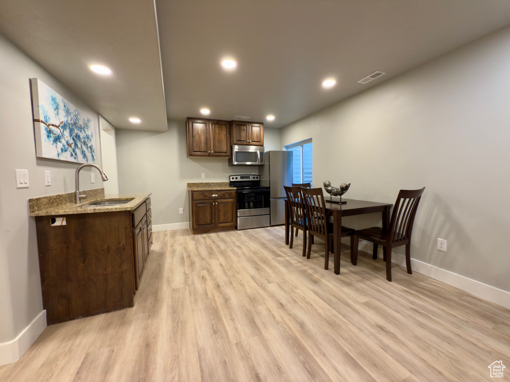 Kitchen featuring appliances with stainless steel finishes, a sink, baseboards, light wood-type flooring, and recessed lighting