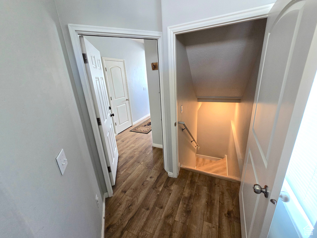 Hallway featuring an upstairs landing, dark wood finished floors, and baseboards