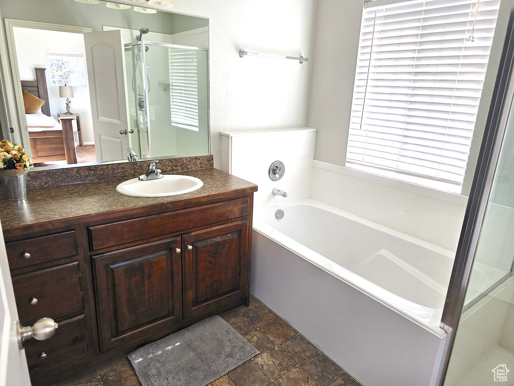 Full bath with a garden tub, a shower stall, vanity, and stone finish flooring