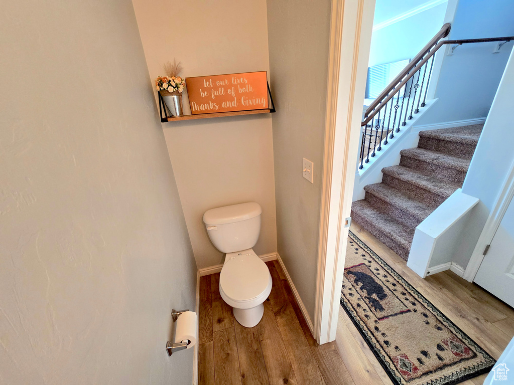 Bathroom featuring wood finished floors, toilet, and baseboards
