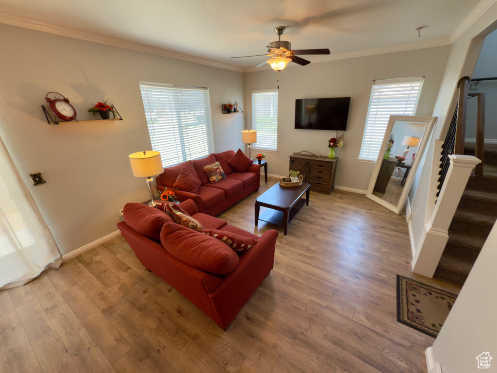 Living room featuring stairway, a ceiling fan, wood finished floors, ornamental molding, and baseboards