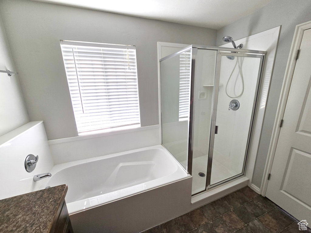 Full bathroom featuring a garden tub, a stall shower, and stone finish floors