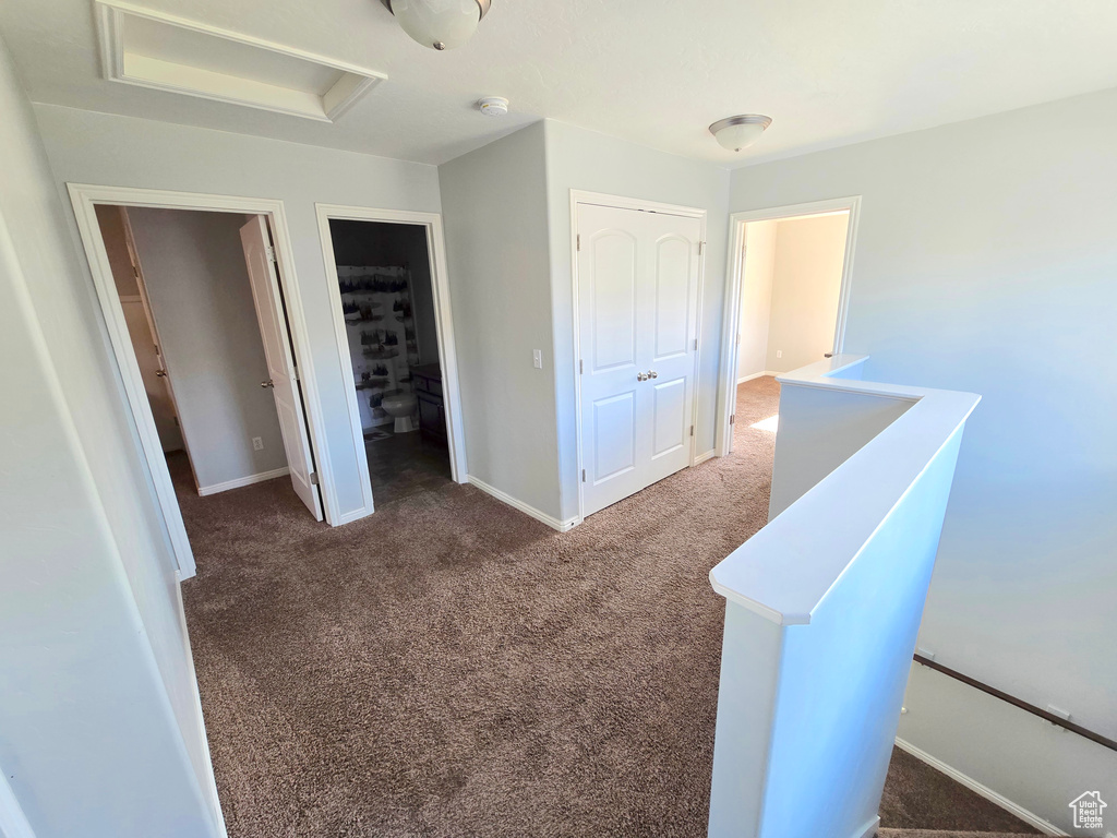Unfurnished bedroom featuring carpet floors, a closet, attic access, and baseboards