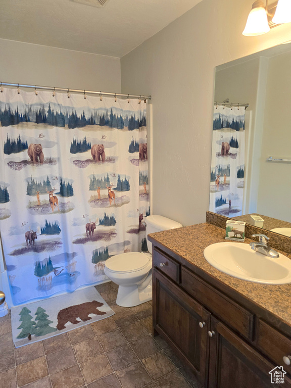 Full bathroom with stone finish floors, vanity, toilet, and curtained shower