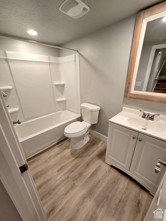 Full bath with toilet, vanity, wood finished floors, shower / tub combination, and baseboards