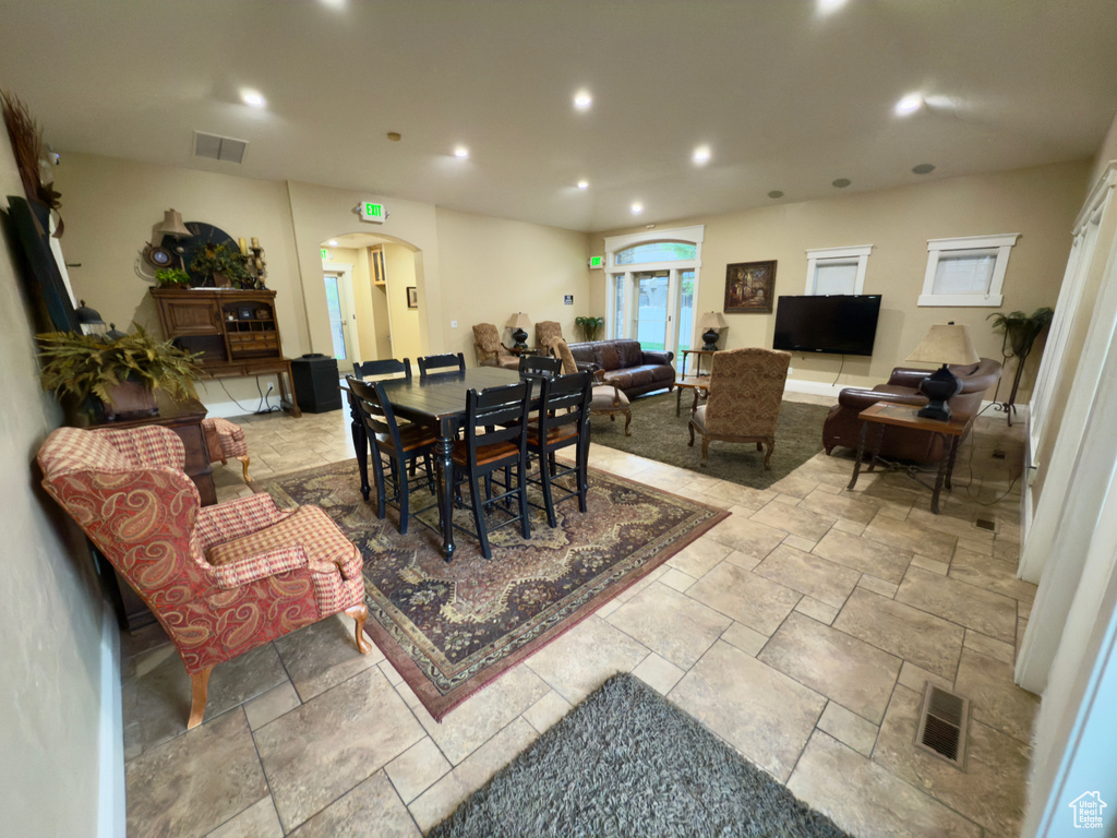 Dining room featuring arched walkways, recessed lighting, and stone tile floors