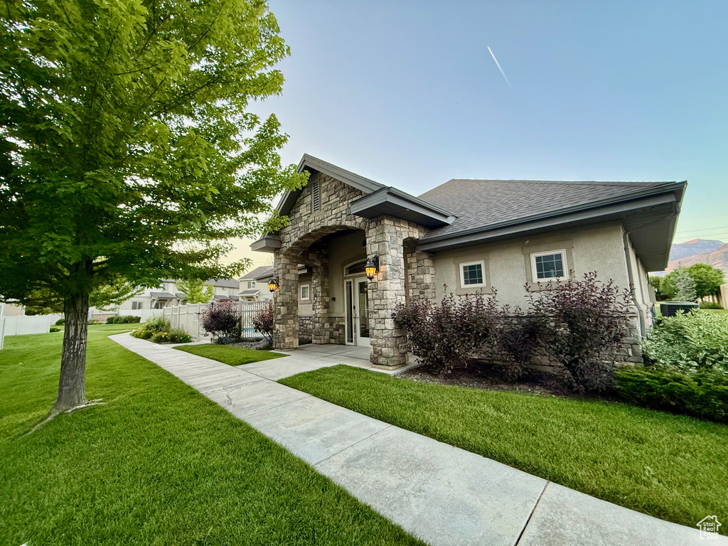View of front of home with stone siding, roof with shingles, and stucco siding