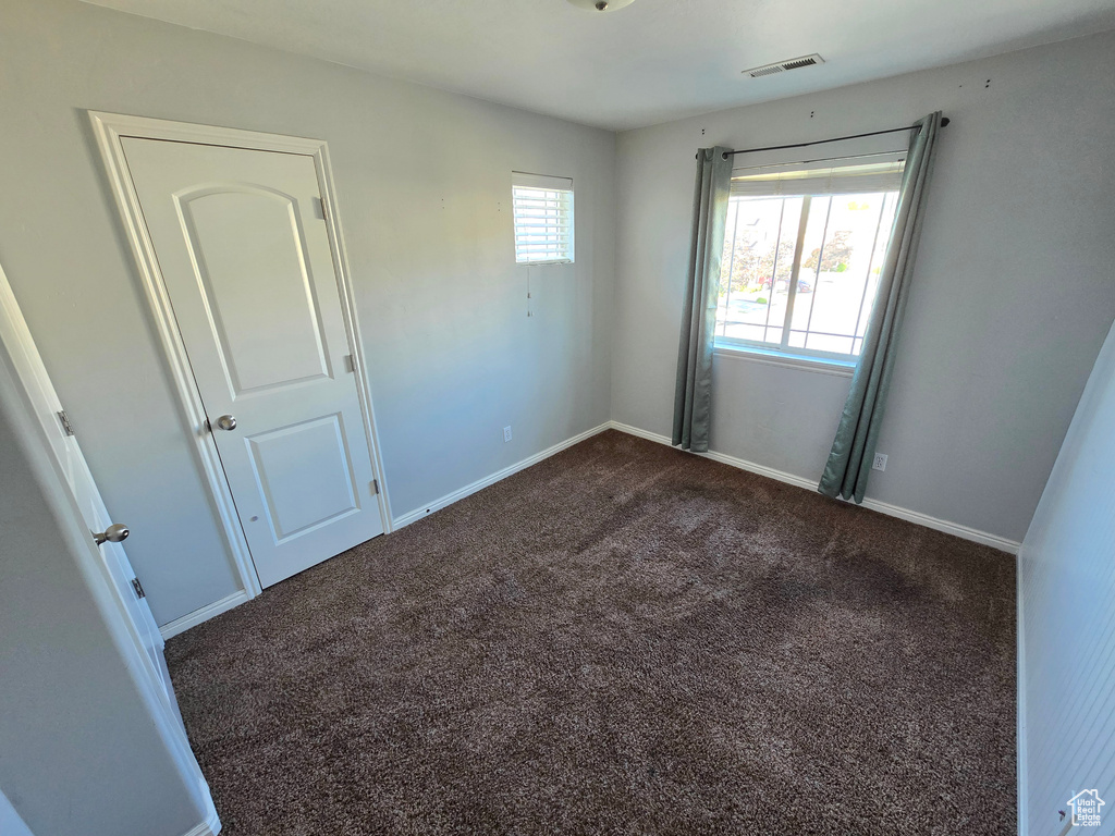 Empty room featuring dark colored carpet and baseboards