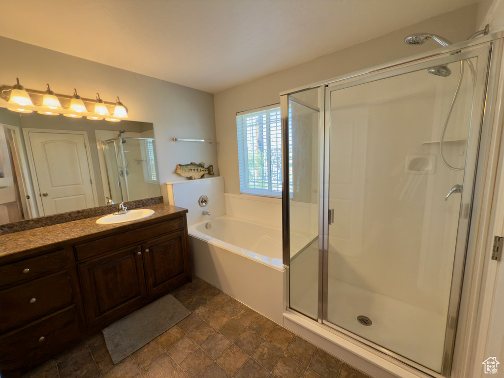Full bath with a stall shower, vanity, a garden tub, and stone finish flooring
