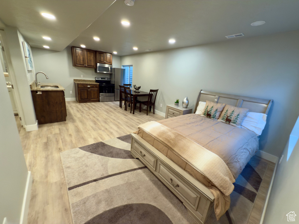 Bedroom featuring light wood-style floors, baseboards, recessed lighting, wet bar, and freestanding refrigerator