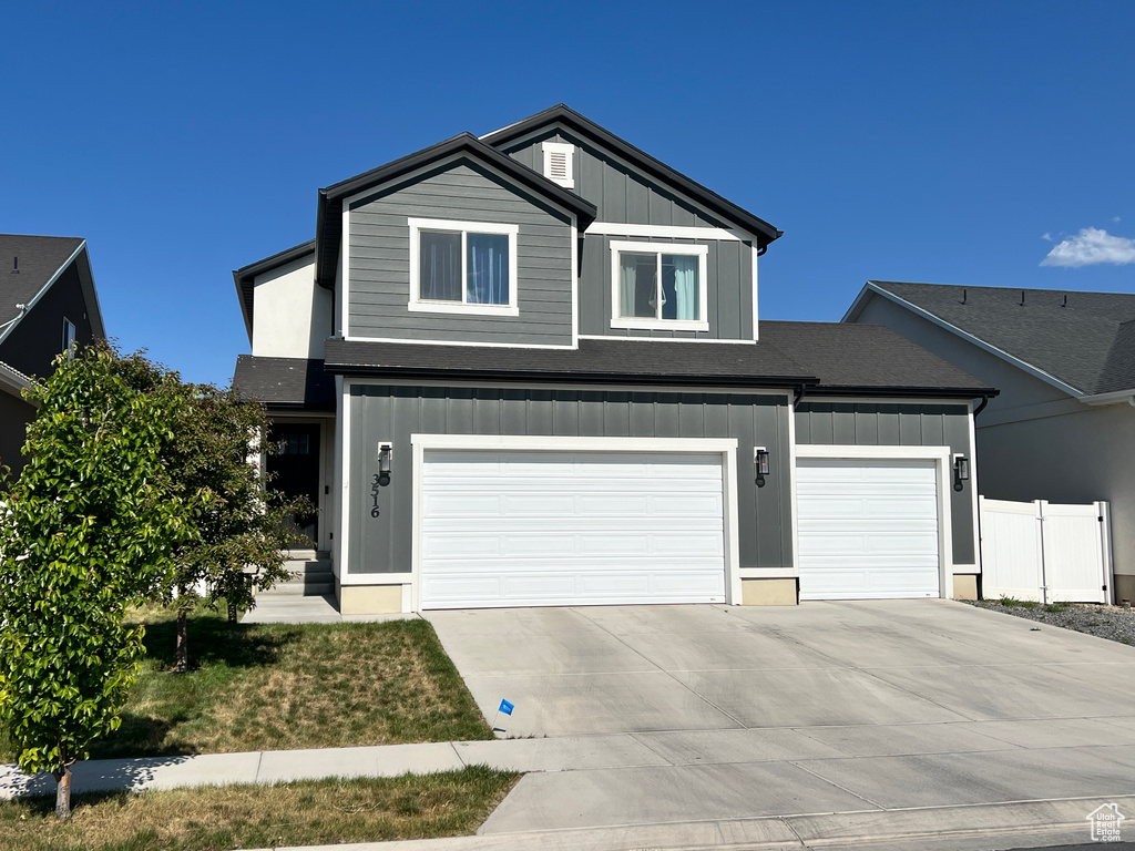 View of front of house featuring driveway, board and batten siding, and an attached garage