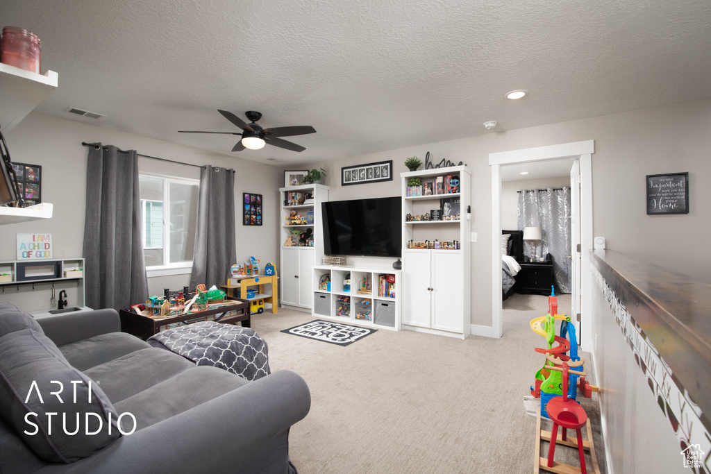 Carpeted living area with ceiling fan, a textured ceiling, recessed lighting, and baseboards