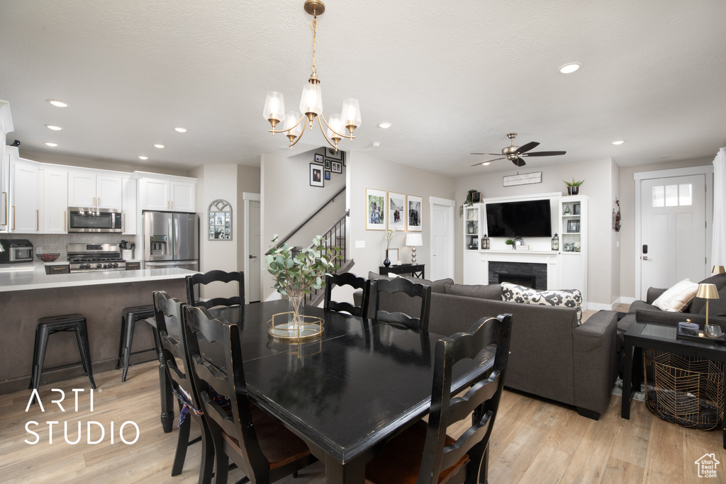 Dining area with light wood finished floors, a ceiling fan, recessed lighting, stairs, and a chandelier
