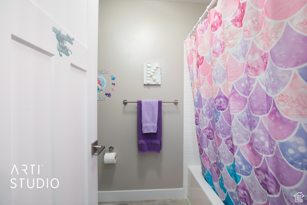 Full bathroom with baseboards and shower / bath combo with shower curtain