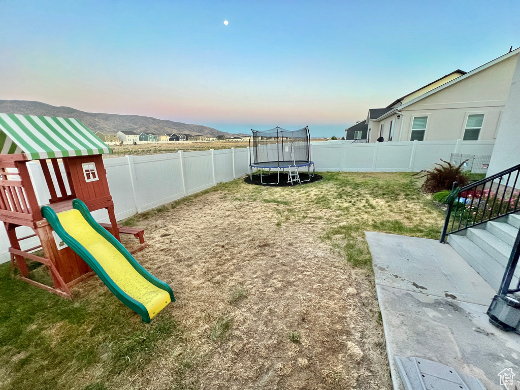 View of yard featuring a trampoline and a playground
