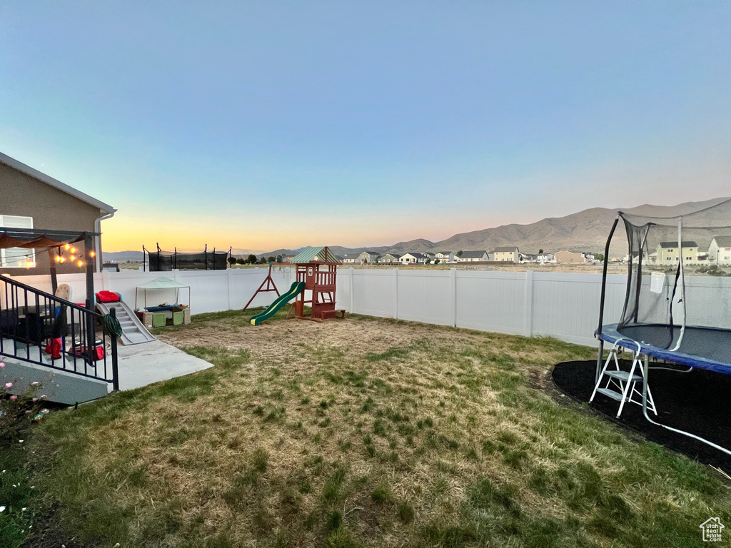 Yard at dusk with a trampoline and a playground