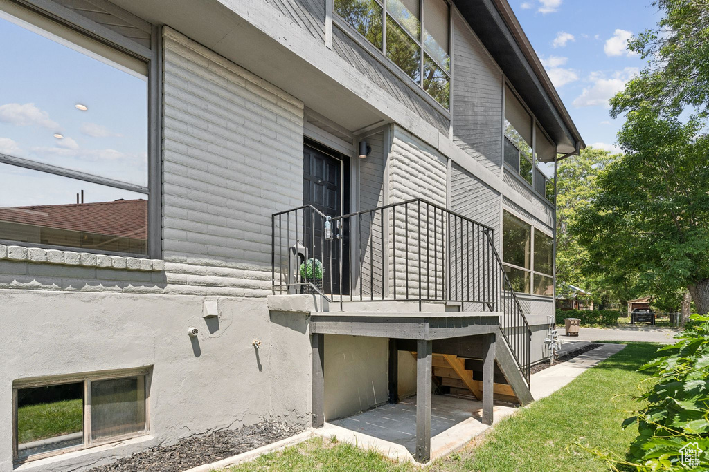 View of side of property with stairs and a yard