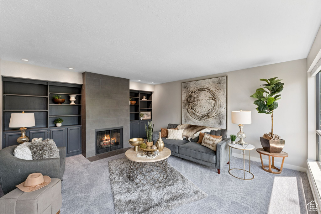 Carpeted living area featuring a tiled fireplace and baseboards