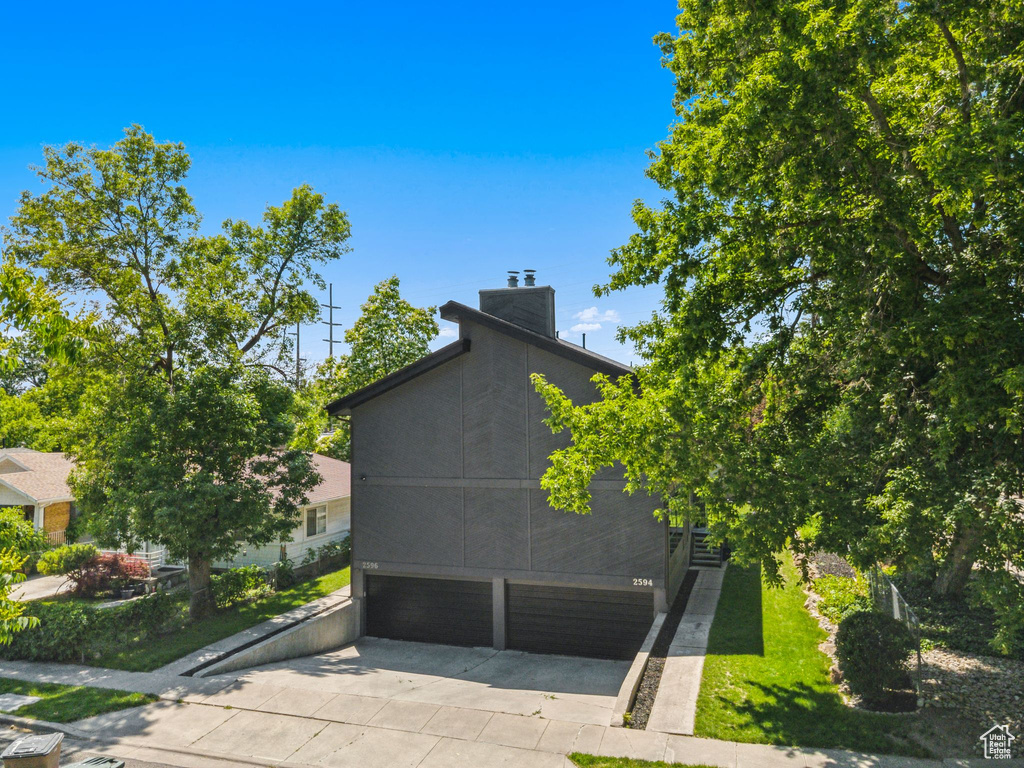 View of side of home featuring an attached garage, driveway, and a chimney