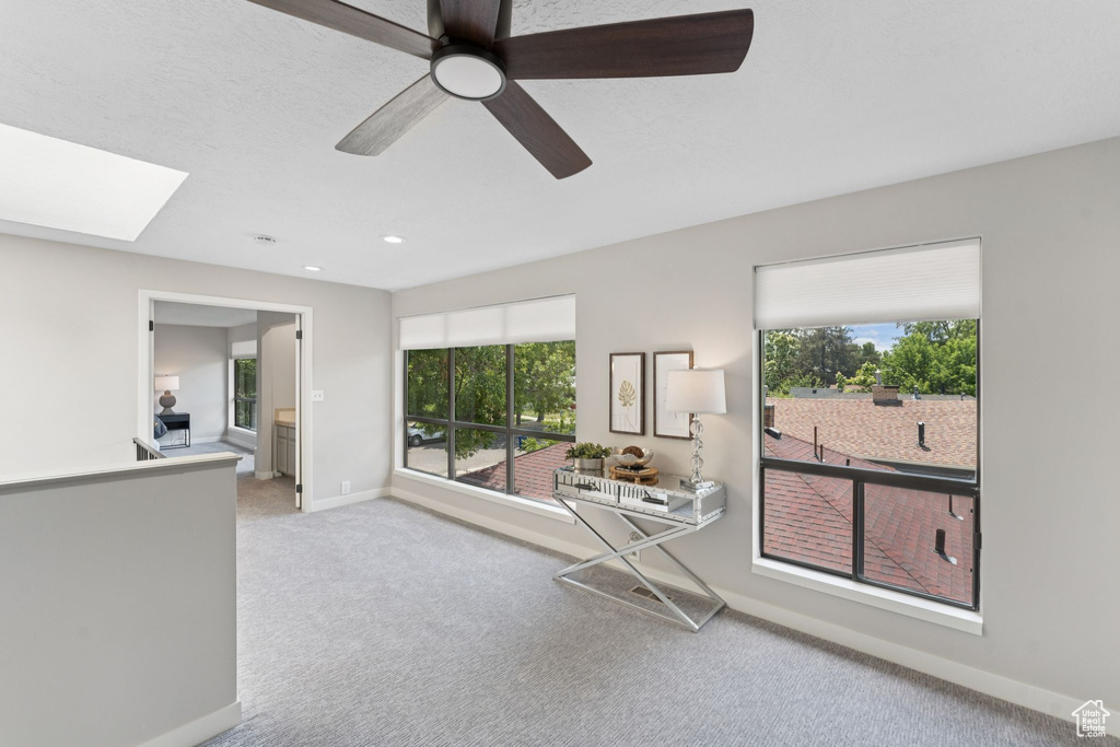 Carpeted living room with plenty of natural light, baseboards, a skylight, a ceiling fan, and recessed lighting