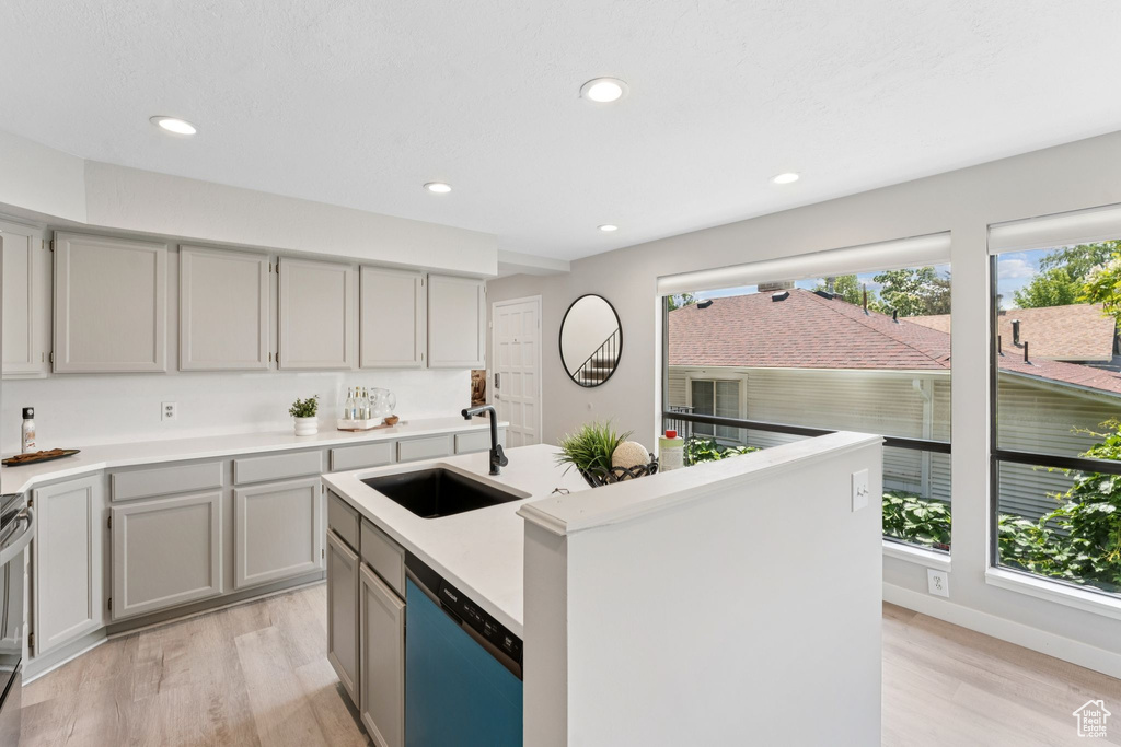 Kitchen with dishwashing machine, a sink, light wood-style floors, gray cabinets, and recessed lighting