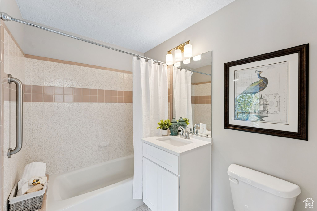 Bathroom featuring vanity, shower / bathtub combination with curtain, and toilet