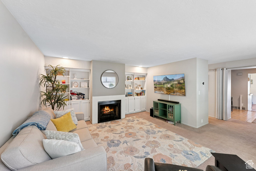Living room featuring a lit fireplace, carpet, baseboards, and built in shelves