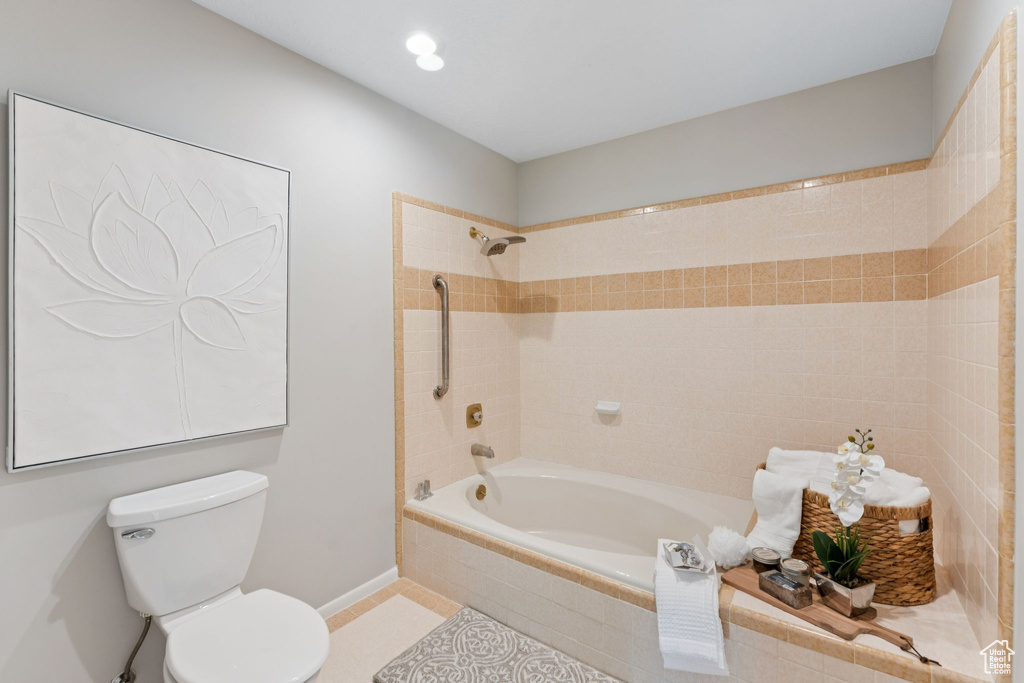 Bathroom featuring toilet, tiled shower / bath, tile patterned floors, and baseboards