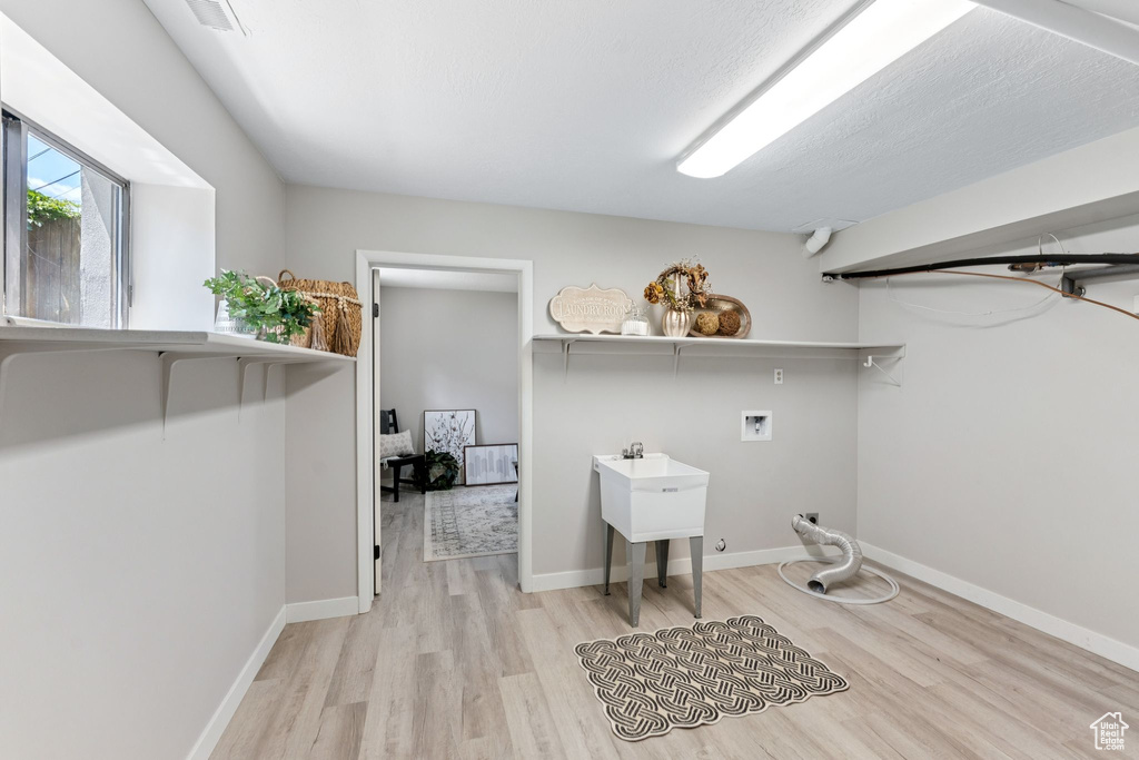 Laundry room with hookup for a washing machine, light wood-style flooring, and baseboards