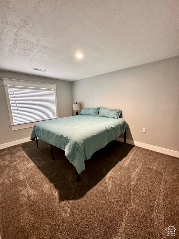 Bedroom with carpet flooring, baseboards, and a textured ceiling