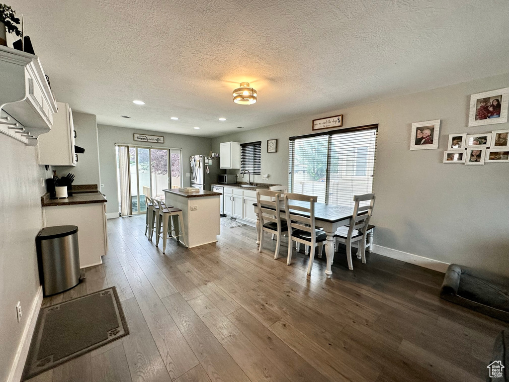 Dining area featuring a textured ceiling, baseboards, recessed lighting, and dark wood-style flooring