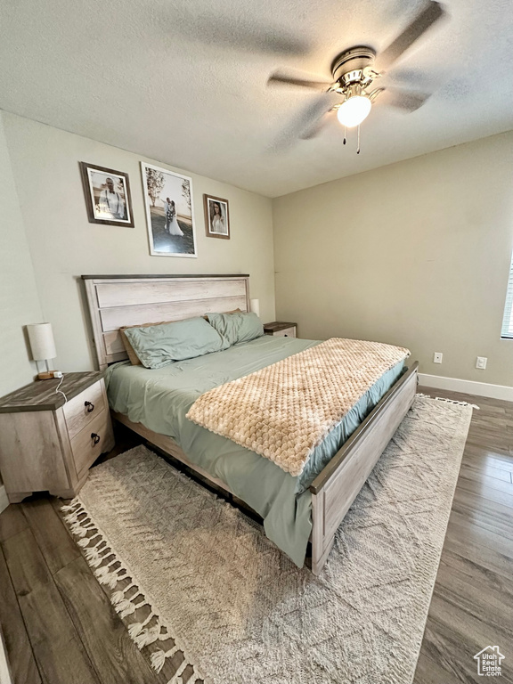 Bedroom with wood finished floors, a textured ceiling, baseboards, and a ceiling fan