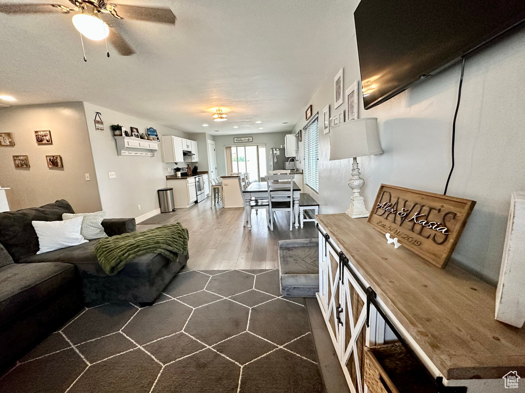 Living area featuring ceiling fan and dark wood-style flooring