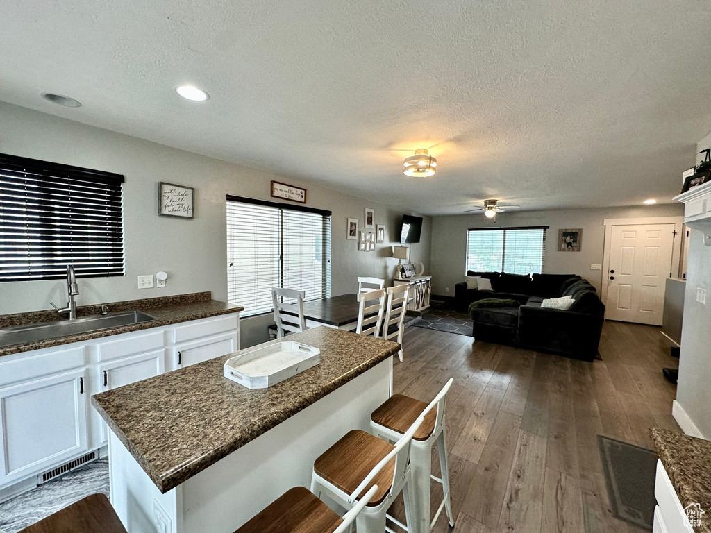 Kitchen featuring a sink, white cabinets, a textured ceiling, a ceiling fan, and dark wood-style flooring