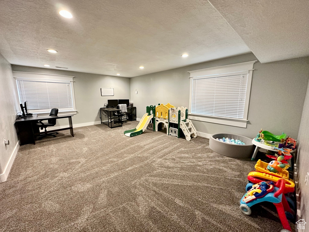 Recreation room featuring a textured ceiling, carpet, a desk, baseboards, and recessed lighting