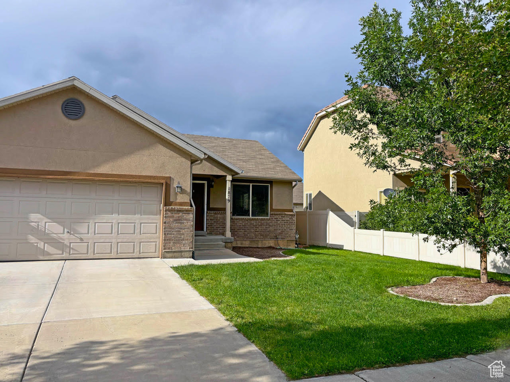 View of front of home featuring stucco siding, a garage, concrete driveway, and brick siding