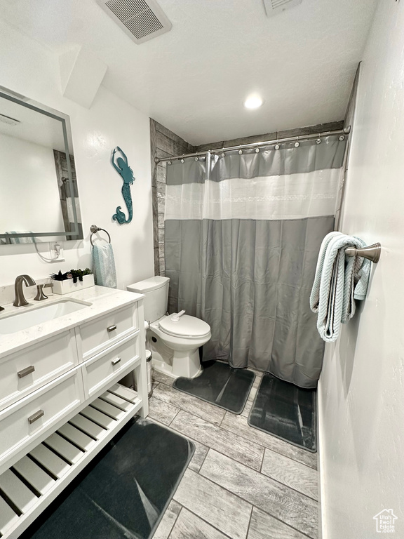Full bathroom with toilet, vanity, and curtained shower