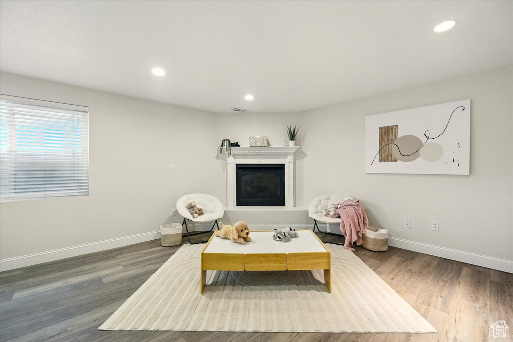 Living area featuring baseboards, wood finished floors, recessed lighting, and a glass covered fireplace