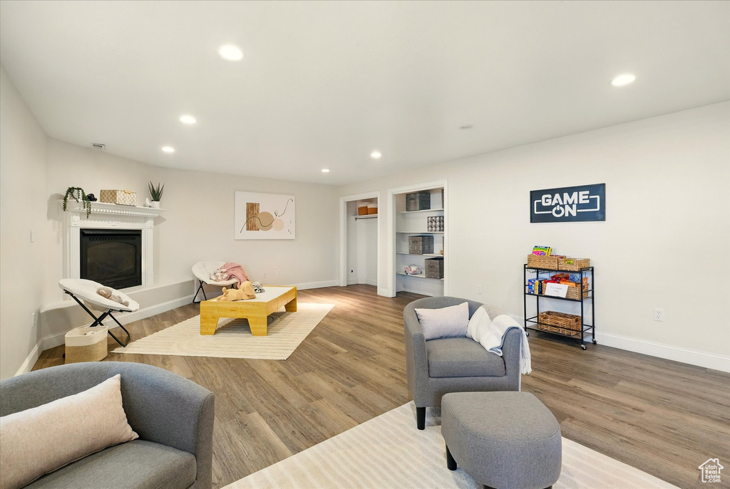 Living room with recessed lighting, baseboards, a glass covered fireplace, and wood finished floors