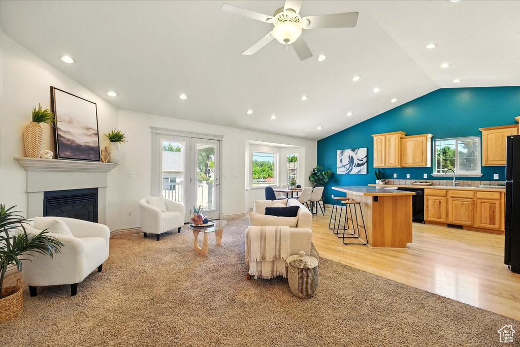 Living area featuring lofted ceiling, recessed lighting, a glass covered fireplace, light wood-style floors, and ceiling fan