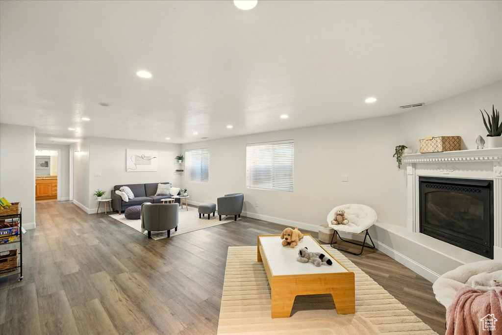 Living room with recessed lighting, a glass covered fireplace, wood finished floors, and baseboards