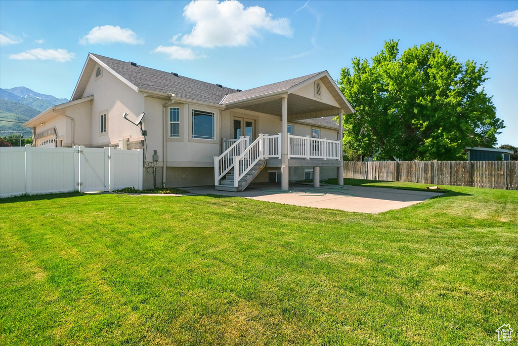Back of house featuring a patio, a gate, stucco siding, and a deck with mountain view