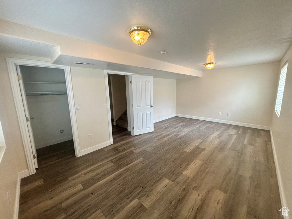 Unfurnished bedroom featuring dark wood-style flooring, a walk in closet, and a closet
