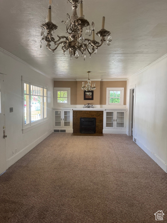 Unfurnished living room with a chandelier, ornamental molding, healthy amount of natural light, a fireplace with flush hearth, and baseboards