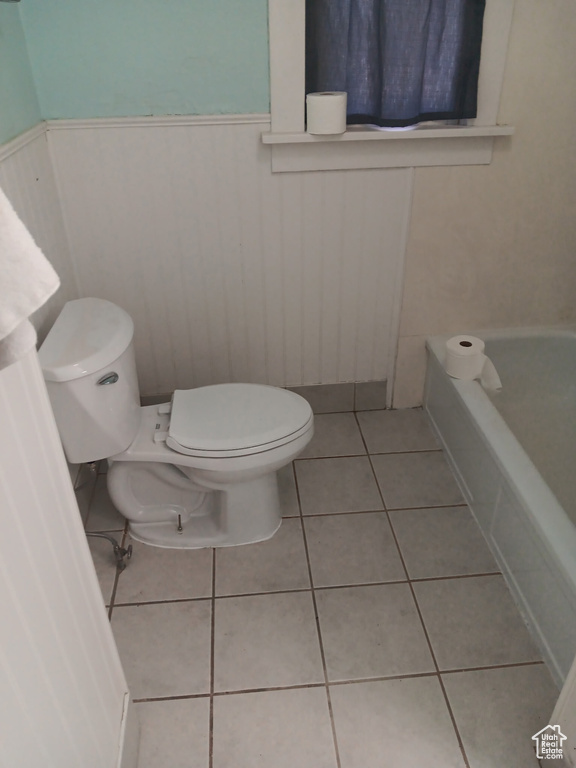 Bathroom featuring wainscoting, a bathtub, and tile patterned flooring
