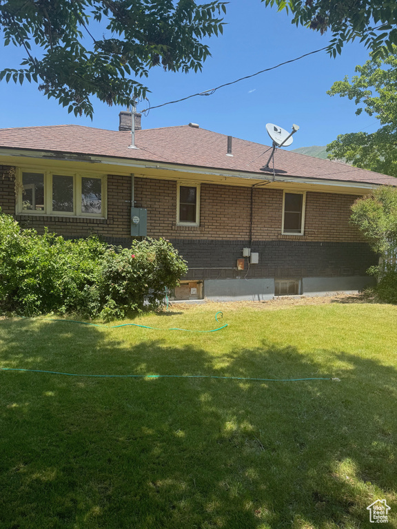Back of property featuring brick siding and a lawn