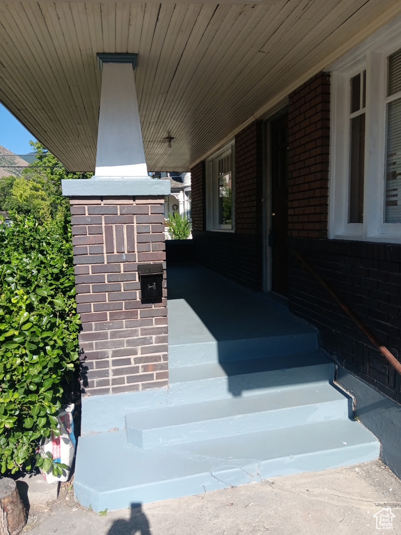 View of exterior entry featuring brick siding and covered porch