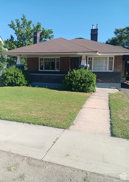 Ranch-style home featuring brick siding, a chimney, and a front lawn