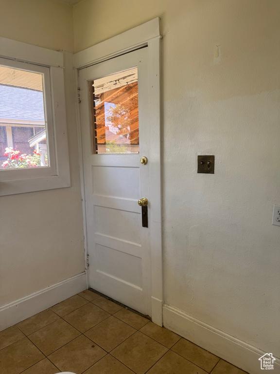 Doorway to outside featuring light tile patterned floors and baseboards