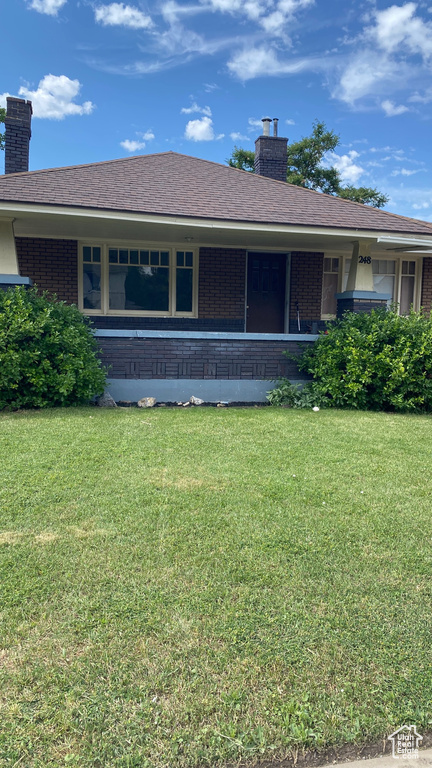 View of front of home with brick siding, a chimney, and a front yard